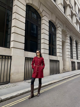 a lady wears a red tweed mini dress with black tights and tall boots